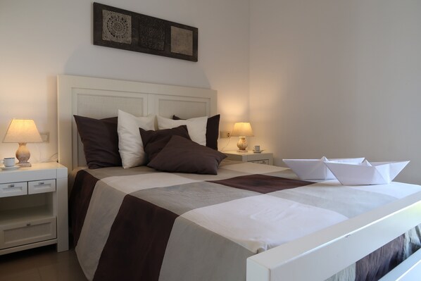 A neatly made bed with a white headboard, two bedside tables with lamps, and a decorative wall piece above the bed. - VILLA S. TOME 8PERS / IND. SWIMMING POOL/ SEA VIEW-IDEAL FAMILY-A600MTRS OF BEACHES (Cap D'Artrutx)