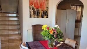 Un comedor con una mesa larga, sillas, un florero y un cuadro en la pared.