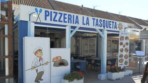 A pizzeria with outdoor seating and a pizza oven display. - AP ECODUNES, Ideal house for your holidays near the sea, free wifi, optional air conditioning, community pool, pets allowed, dog’s beach (Delta de l'ebre)