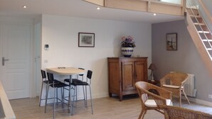A dining area with a table and chairs, a wooden cabinet, and a wicker chair.