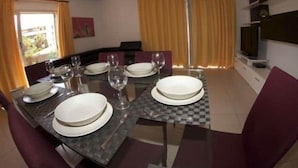 Comedor con una mesa dispuesta para cuatro personas, incluyendo platos, vasos y cubiertos.
