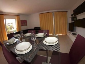 A dining area with a table set for four, including plates, glasses, and cutlery.
