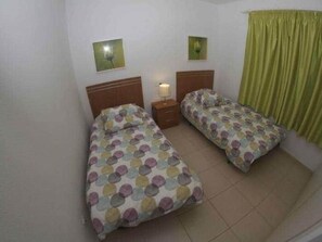 A room with two single beds, a nightstand with a lamp, and a green curtain. - BEAUTIFUL HOLIDAY HOME 84 WITH PRIVATE POOL (Callao Salvaje)