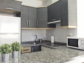 A kitchen with granite countertops, a white refrigerator, a microwave, and dark cabinetry. - BEAUTIFUL HOLIDAY HOME 84 WITH PRIVATE POOL (Callao Salvaje)