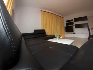 A modern living room with a black leather sofa, a white coffee table, and a yellow curtain. - BEAUTIFUL HOLIDAY HOME 84 WITH PRIVATE POOL (Callao Salvaje)