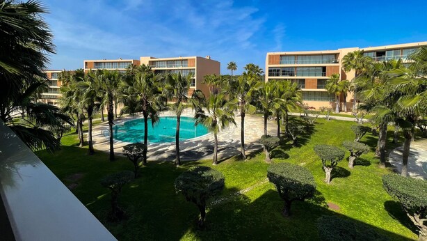 A pool surrounded by palm trees and modern buildings. - Herdade dos Salgados, T1-10A-2D - Pool View, (Albufeira)