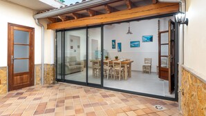 A dining area with a wooden table and chairs, a glass sliding door, and a tiled floor. - CAN TONI,  Apartment, 100 m from the white sand beach, for 6 People (Alcúdia)