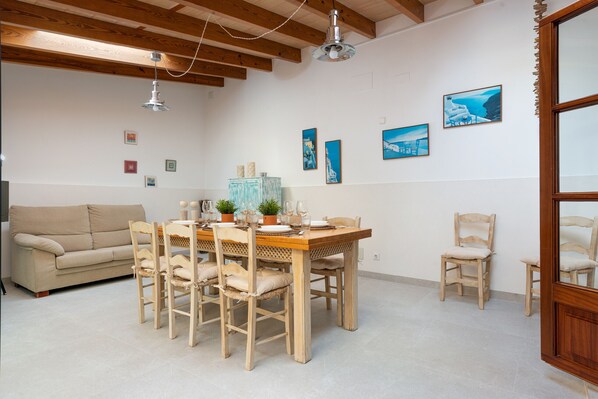 A dining area with a wooden table and chairs, a sofa, and wall art.