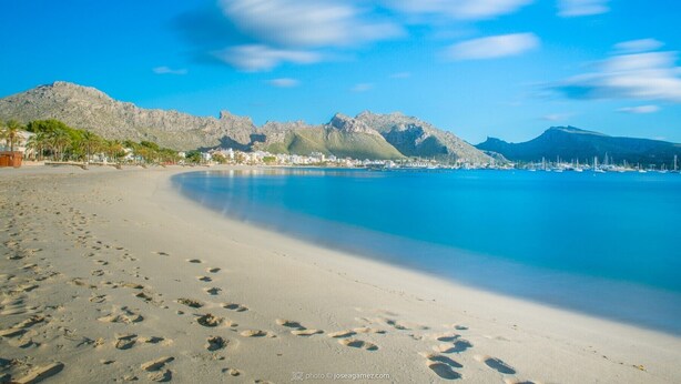 A beach with footprints leading to the water, a mountain in the background, and a clear sky. - CAN TONI,  Apartment, 100 m from the white sand beach, for 6 People (Alcúdia)