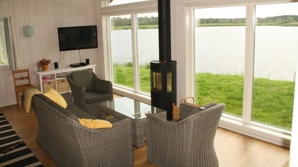 Una sala de estar con muebles de mimbre, una mesa de centro de cristal, una chimenea y un televisor.
