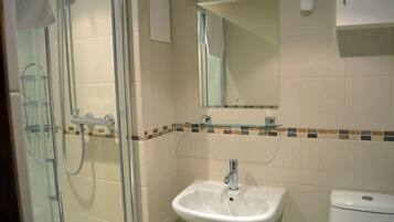 Une salle de bain avec une douche à parois de verre, un lavabo blanc et des toilettes.