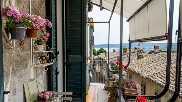 Un balcon avec vue sur la mer, une table décorée de bougies et des plantes en pot.
