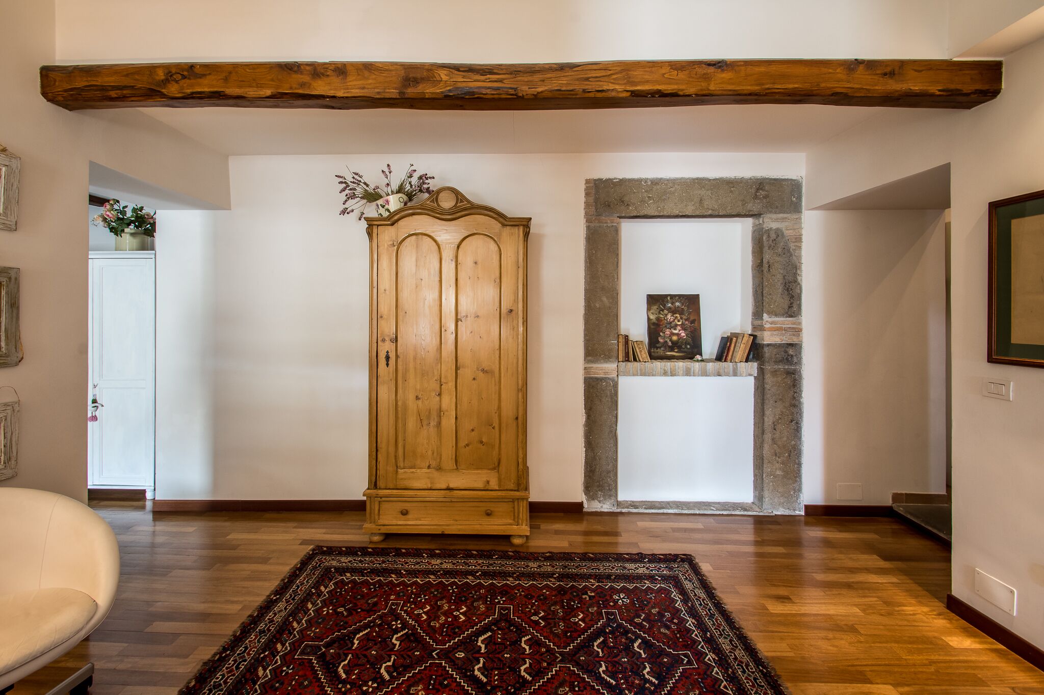 Une pièce avec un meuble en bois, un tapis à motifs et un mur en pierre.