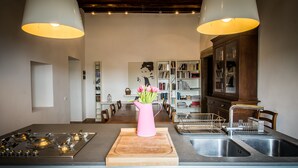 Une cuisine moderne dotée d’un îlot central, d’appareils électroménagers en acier inoxydable et d’un vase rose orné de fleurs.