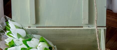 A rustic wooden chest with a rope handle, containing a bouquet of white flowers.