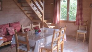 A wooden cabin interior with a dining table, chairs, a sofa, and a staircase. - Chalet - CHORGES (Chorges)