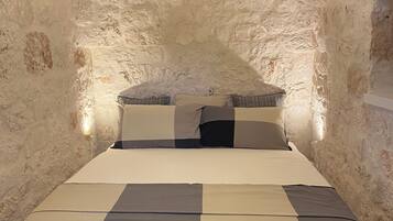 Ein Bett in einem Raum mit Steinsäulen und einer Bettdecke mit Schachmuster sowie Kissen.