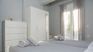 Camera da letto con due letti, un armadio e una finestra con tende.