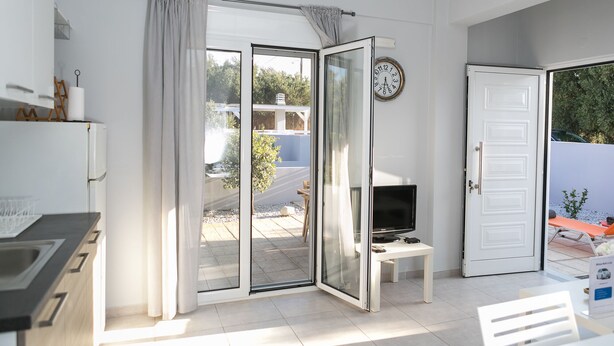 Una camera moderna con una porta scorrevole in vetro che dà su un patio, una televisione a schermo piatto e una porta bianca.