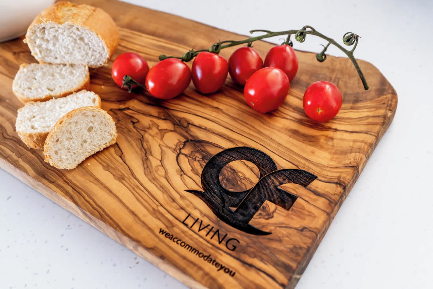 Een houten snijplank met sneetjes brood en kersen tomaten.
