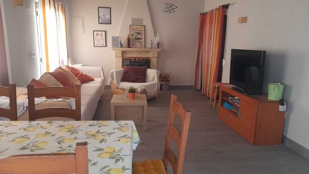 A cozy living room with a fireplace, a television, and a dining area with a table. - Detached villa with swimming pool (Dénia)