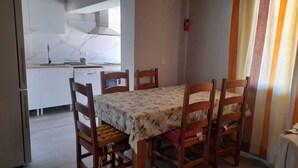 A dining area with a table and chairs, a kitchen in the background, and a window with curtains. - Detached villa with swimming pool (Dénia)