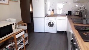 A compact kitchen with a washing machine, microwave, and a small dining area. - Detached villa with swimming pool (Dénia)