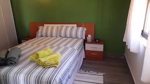A bed with striped bedding, a bedside table with a lamp, and a rolled-up towel on the floor. - Detached villa with swimming pool (Dénia)