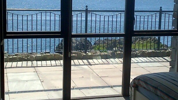 Un balcón con vista al mar y montañas a lo lejos.