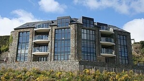 Un edificio moderno con varios balcones, amplias ventanas y fachada de piedra.