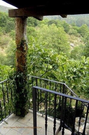 A balcony with a wrought iron railing overlooking a lush, green landscape.