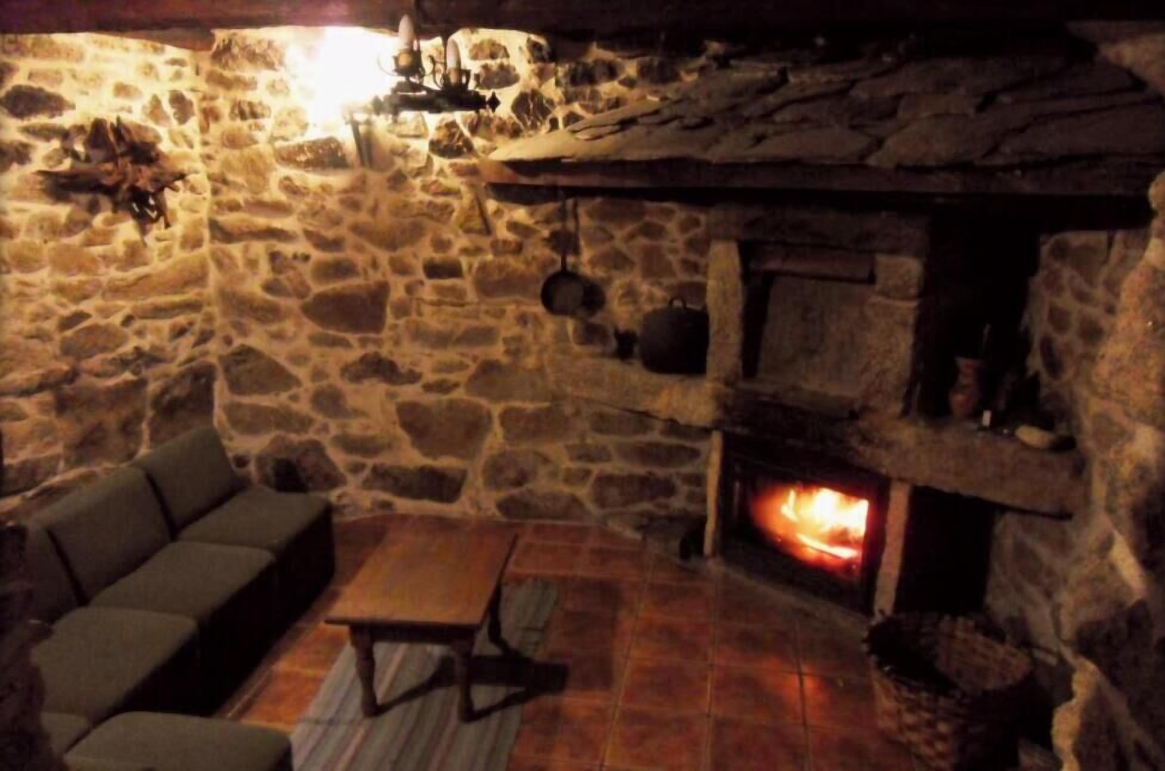 A stone-walled room with a fireplace, a sofa, and a table.