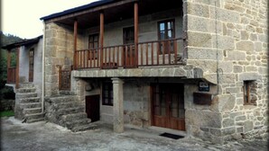 Un edificio de piedra con un balcón, puertas de madera y una escalera que lleva a la entrada.