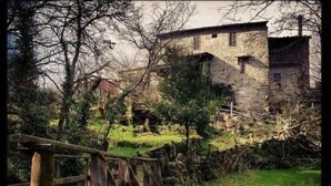 Un edificio de piedra rústico con un puente de madera sobre un arroyo.