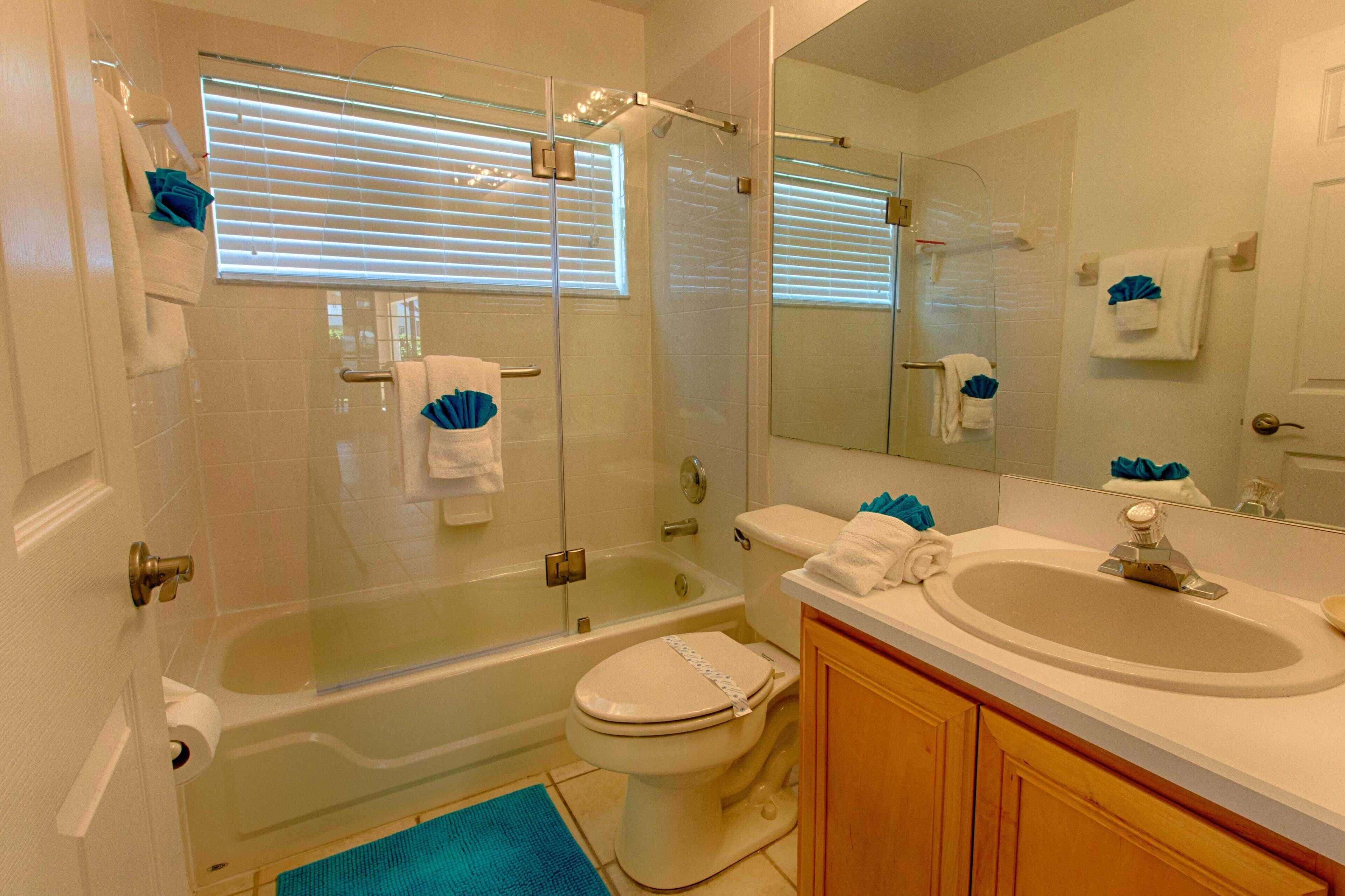 A bathroom with a bathtub, toilet, sink, and a large mirror.