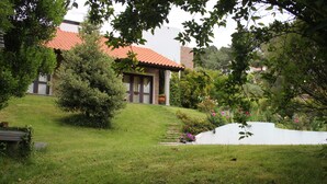 Ein Haus mit rotem Ziegeldach, umgeben von einem gepflegten Rasen und Garten.