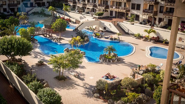 Ein Resort mit mehreren Schwimmbecken, einer Brücke und verschiedenen Sitzbereichen im Freien.