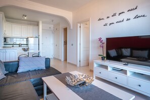 A modern living room with a sofa, a TV, and a wall with a motivational quote.