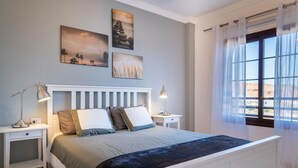 Ein Schlafzimmer mit einem Bett, zwei Nachttischen und einem Fenster mit Vorhängen.
