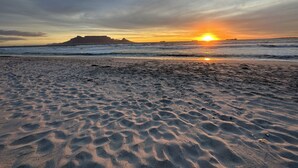 Una playa con arena y olas al atardecer.