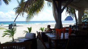 A beachside restaurant with outdoor seating, a view of the ocean, and a signboard. - Blue Diamond Paradise A little corner of paradise with a breathtaking sea view (diamant)