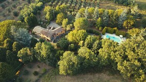 An aerial view of a property with a large house, a swimming pool, and dense surrounding trees. - ancient villa with pool and park in total privacy (tuoro sul trasimeno)