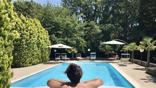 A swimming pool with lounge chairs and umbrellas, surrounded by trees. - ancient villa with pool and park in total privacy (tuoro sul trasimeno)
