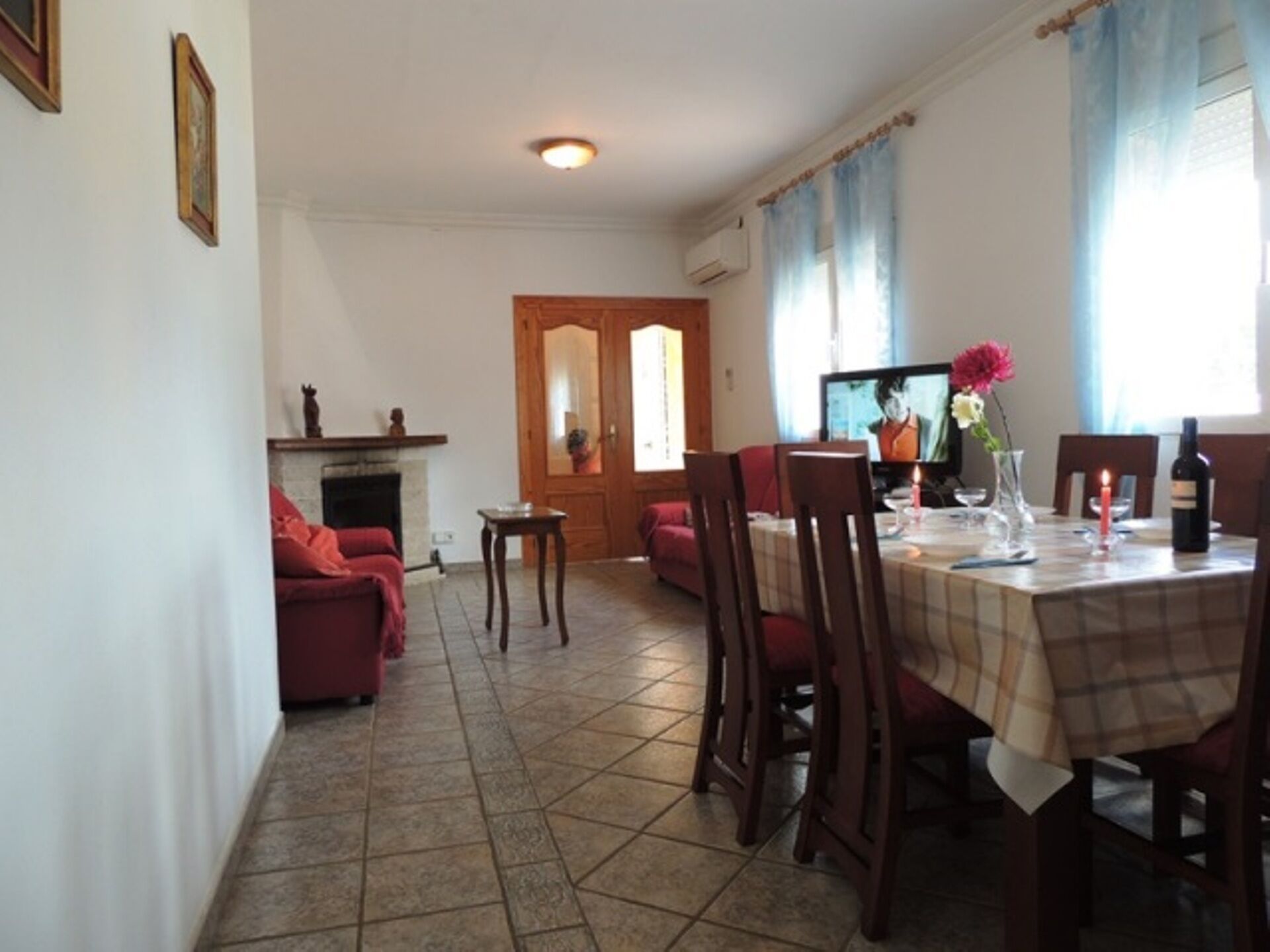 Un coin repas avec une table dressée pour quatre personnes, une cheminée et un téléviseur.