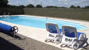 Une piscine avec deux chaises longues et une couverture bleue sur le côté gauche.