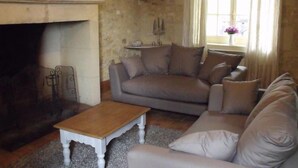 Un salon avec une cheminée, un canapé, une table basse et une fenêtre avec des rideaux.