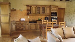 Une cuisine chaleureuse avec des meubles de rangement en bois, une table à manger et un canapé.