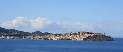 A coastal town with buildings on a hillside and a lighthouse on a small island.