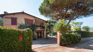 A house with a covered porch, a brick wall, and a large tree in front. - Villa Giolù, Appartamento Corallo 200 m from the sea, ferry discount! (Portoferraio)