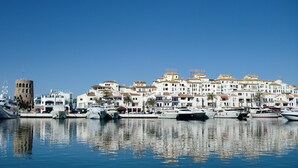 Un puerto deportivo con barcos amarrados, una torre destacada y una hilera de edificios con letreros que indican "HOTEL".